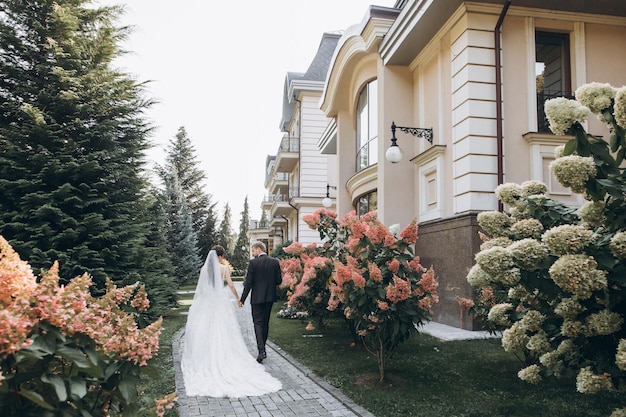 hermosos novios se abrazan en un área grande, detrás de ellos un palacio de color claro