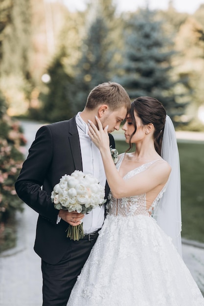 hermosos novios se abrazan en un área grande, detrás de ellos un palacio de color claro