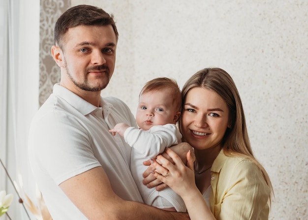 Hermosos padres jóvenes sosteniendo a su linda hija