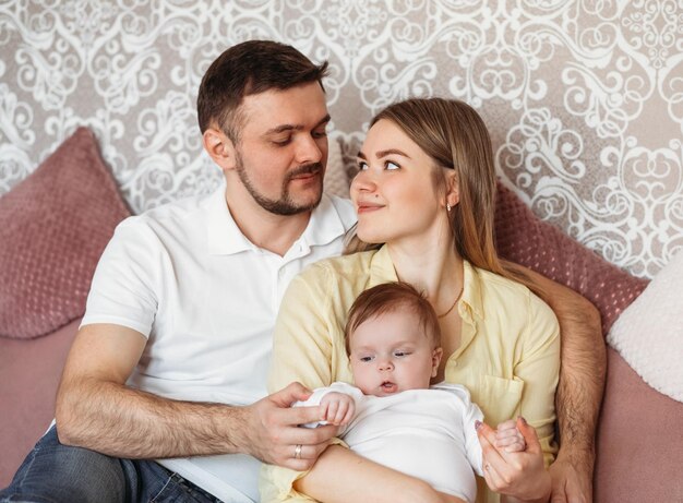 Hermosos padres jóvenes sosteniendo a su linda hija