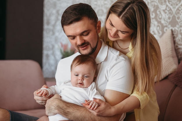 Hermosos padres jóvenes sosteniendo a su linda hija