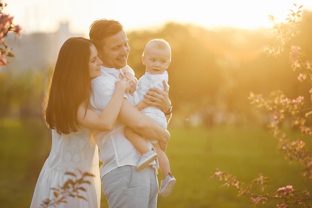 Hermosos padres jóvenes y su pequeño hijo lindo abrazando y sonriendo al atardecer