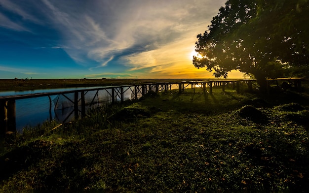 Hermosos paisajes de puesta de sol con puente de madera