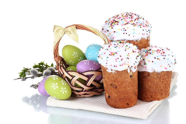 Hermosos pasteles de Pascua coloridos huevos en canasta y flores aisladas en blanco