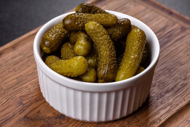 Hermosos pepinos en escabeche de tamaño pequeño sobre un fondo de hormigón oscuro