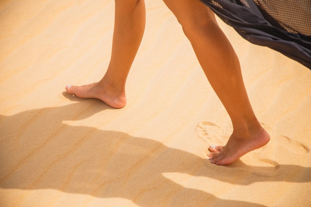 Hermosos pies femeninos caminando bajo el desierto