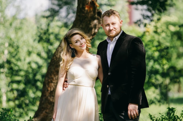 hermosos recién casados caucásicos en el jardín con el telón de fondo de la vegetación.