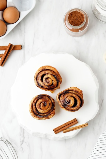 Foto hermosos rollos de canela frescos de cerca en la mesa blanca fragantes pasteles caseros