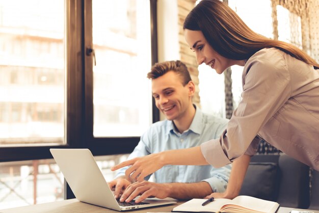 Hermosos socios comerciales jóvenes están utilizando una computadora portátil.