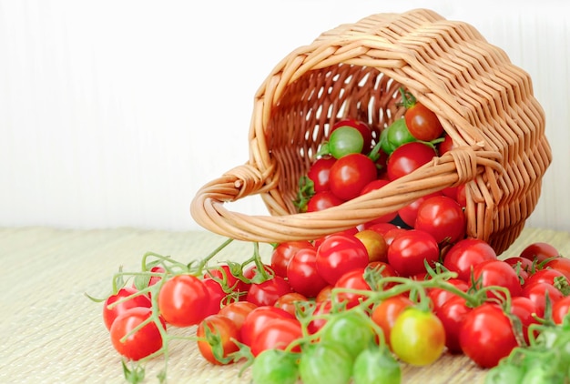 Hermosos tomates cherry que se cayeron de la canasta sobre la mesa