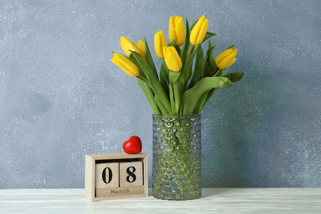 Hermosos tulipanes amarillos en un florero de cristal sobre blanco para el Día de la Madre