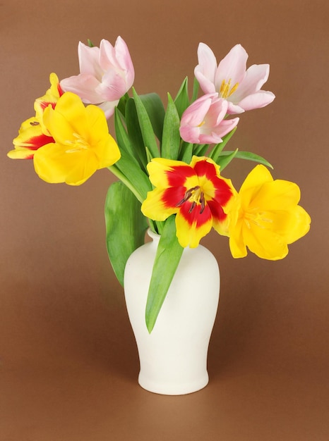 Hermosos tulipanes en balde sobre fondo marrón