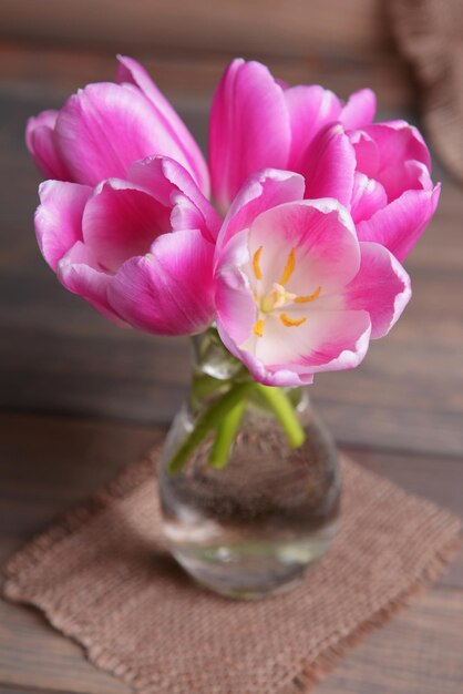 Hermosos tulipanes en cubo en jarrón sobre mesa sobre fondo gris