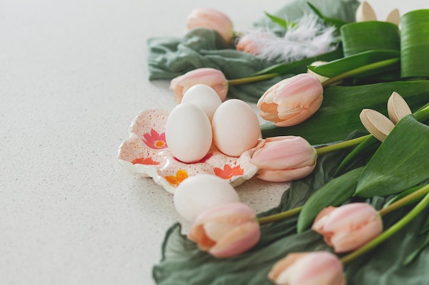 Hermosos tulipanes huevos naturales y decoración de conejitos en una mesa moderna Elegante bodegón de Pascua con espacio para copiar Felices Pascuas Portahuevos hecho a mano tulipanes rosas y orejas de conejo de madera