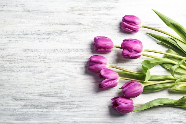 Hermosos tulipanes lilas sobre fondo de madera clara