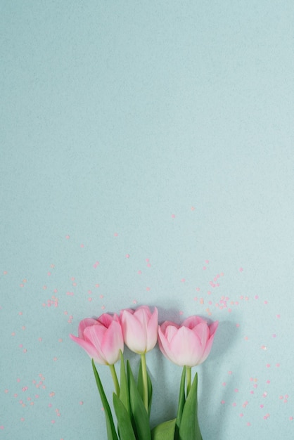 Hermosos tulipanes de primavera rosa sobre un fondo de menta claro con lentejuelas rosas yacen planas. Una copia del espacio. Tarjeta de San Valentín, Cumpleaños, Aniversario, 8 de marzo, Pascua