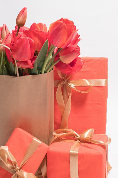 Hermosos tulipanes rojos en una bolsa de regalo y cajas de regalo.