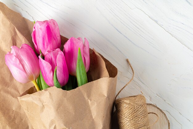 Hermosos tulipanes rosados frescos en la mesa de madera blanca de cerca