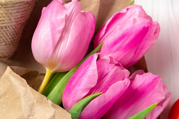 Hermosos tulipanes rosados frescos en la mesa de madera blanca de cerca