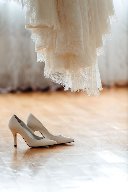 Hermosos zapatos de boda y vestido en un piso de madera marrón