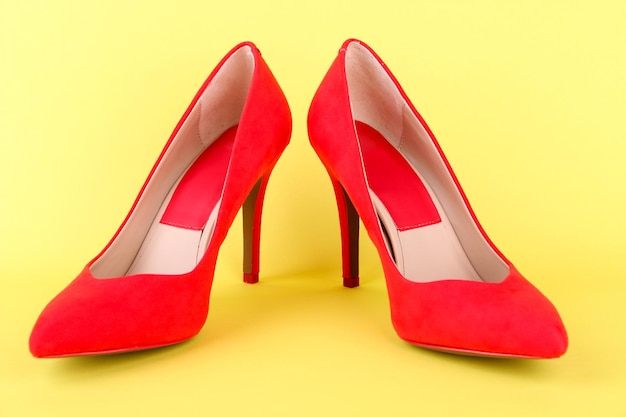 Hermosos zapatos femeninos rojos sobre fondo amarillo