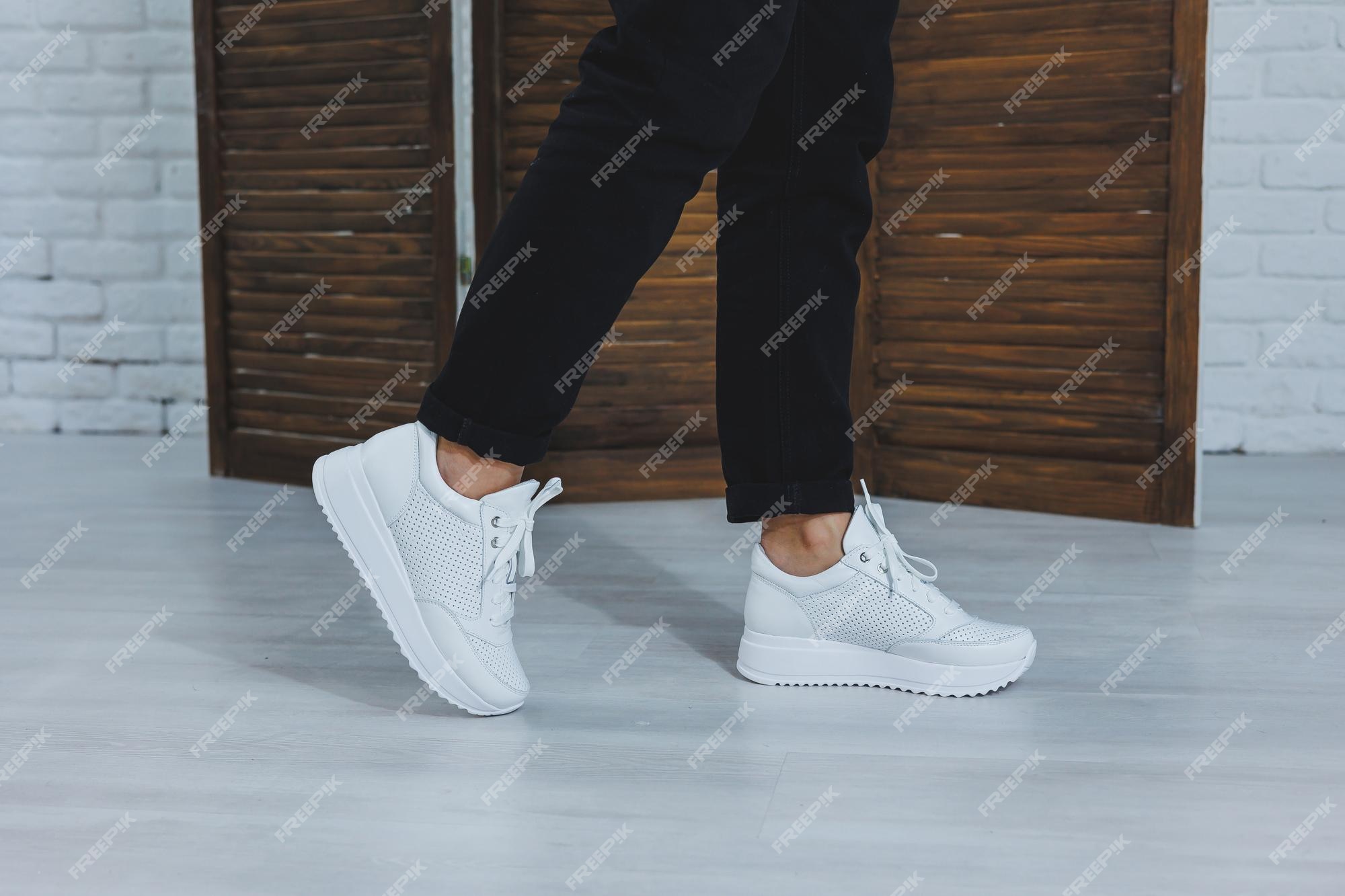 Hermosos zapatos de mujer con zapatillas blancas de cuero en el interior de una habitación o zapatos de para una mujer pantalones negros y zapatillas blancas estilo casual y moderno moderno