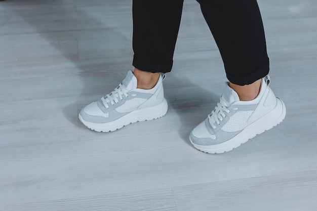 Hermosos zapatos de mujer con zapatillas blancas de cuero en el interior de una habitación o zapatos de oficina para una mujer pantalones negros y zapatillas blancas estilo casual y moderno moderno y de moda