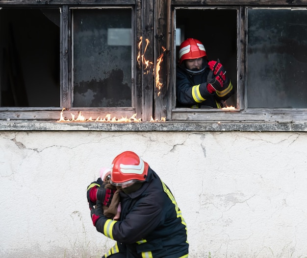 Héroe bombero sacando a una niña del área del edificio en llamas por un incidente de incendio. Rescatar a la gente de un lugar peligroso. Trabajo en equipo Foto de alta calidad