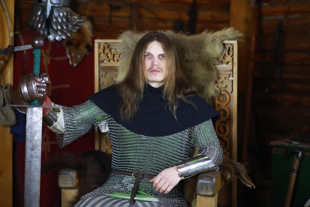 Foto un héroe poderoso con el pelo largo en una armadura de cota de malla en un antiguo salón. guerrero medieval en los aposentos del caballero.