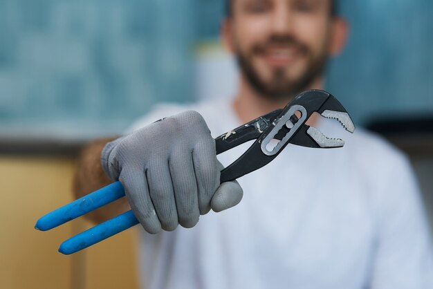 Herramienta de mano necesaria primer plano de la mano del joven reparador sosteniendo una llave de tubo