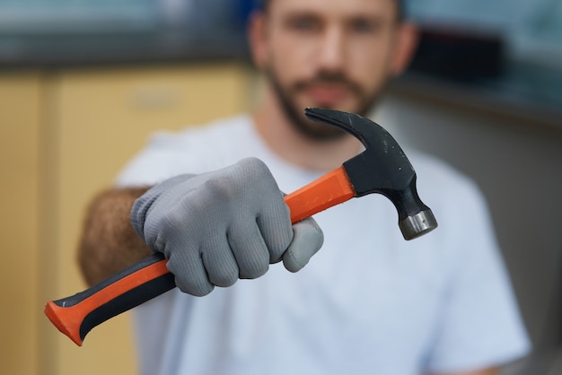 Herramienta de mano necesaria primer plano de la mano del joven reparador sosteniendo un martillo