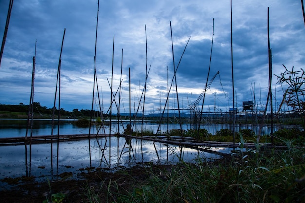 Herramienta de pesca tradicional o trampa de peces de bambú en la silueta del paisaje de la luz del atardecer