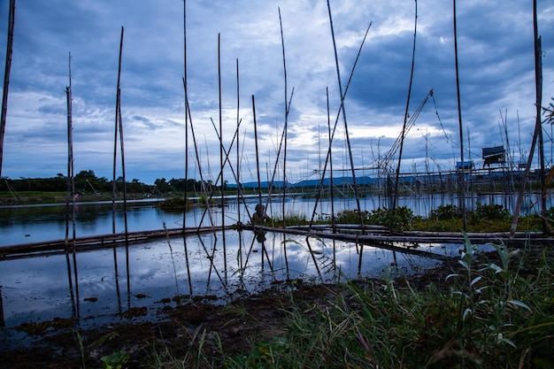 Herramienta de pesca tradicional o trampa de peces de bambú en la silueta del paisaje de la luz del atardecer