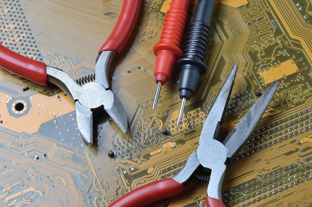 La herramienta de reparación de componentes electrónicos se encuentra en la placa base de la computadora. de cerca.