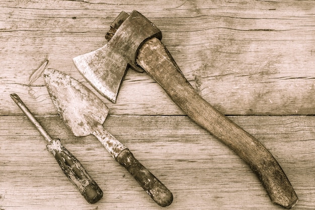 Herramientas antiguas sobre fondo de madera. Hacha, paleta y destornillador manchados viejos en la superficie de madera vieja. Estilo vintage