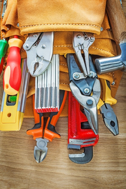 Foto herramientas de construcción en cinturón de construcción de cuero sobre tablero de madera