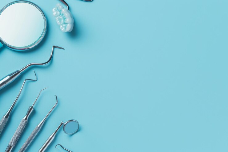 Herramientas dentales y un modelo de dientes exhibidos en un fondo azul claro