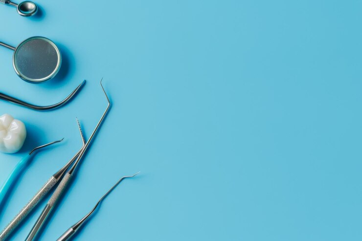 Herramientas dentales y un modelo de dientes exhibidos en un fondo azul claro