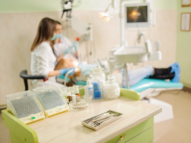 Herramientas dentales en primer plano y dentista haciendo el primer chequeo.