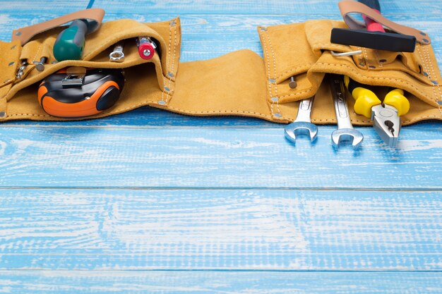 Foto herramientas e instrumentos en el cinturón en la mesa de madera en el frente, superficie de textura de fondo de tablero de tablón