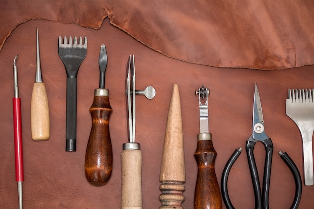 Herramientas para la elaboración y piezas de cuero marrón. Maquetación sobre fabricación de marroquinería. Vista desde arriba
