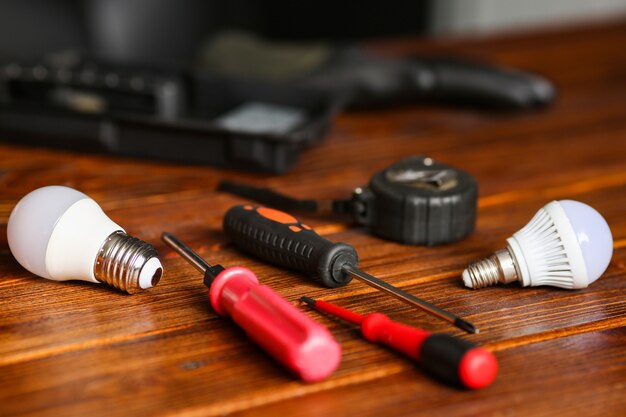 Las herramientas del electricista están sobre la mesa. El proceso de reparación de equipos, sustitución de lámparas, destornilladores, guantes en el lugar de trabajo. Foto de alta calidad