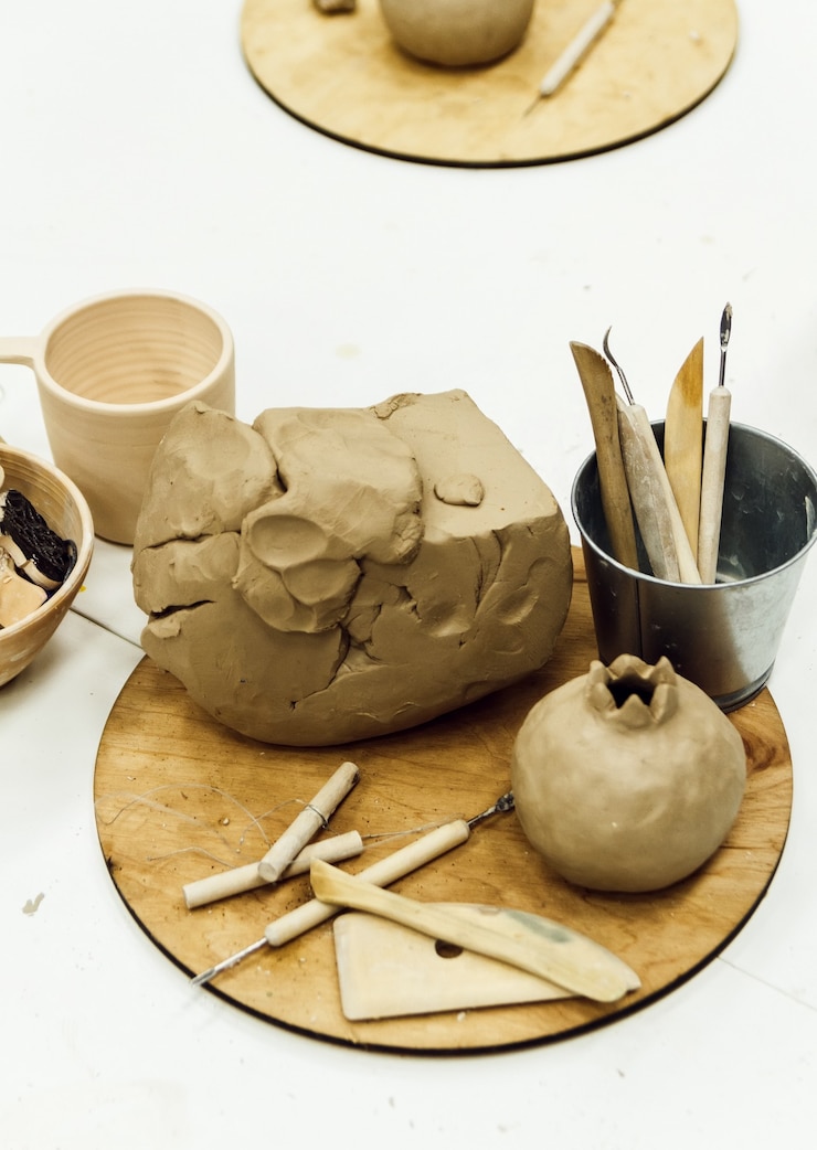 Foto herramientas de escultura de primer plano en mesa, pilas de arcilla, algunos perfiles.