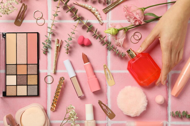 Herramientas de maquillaje y flores sobre un fondo rosa.