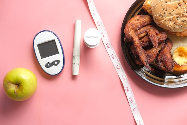 Herramientas de medición para diabéticos y manzana en comparación con la comida chatarra