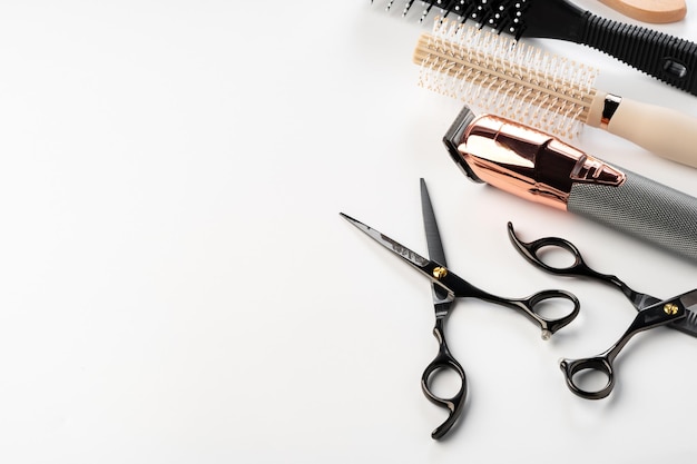 Herramientas negras para la peluquería y diversos cepillos para el cabello sobre fondo blanco