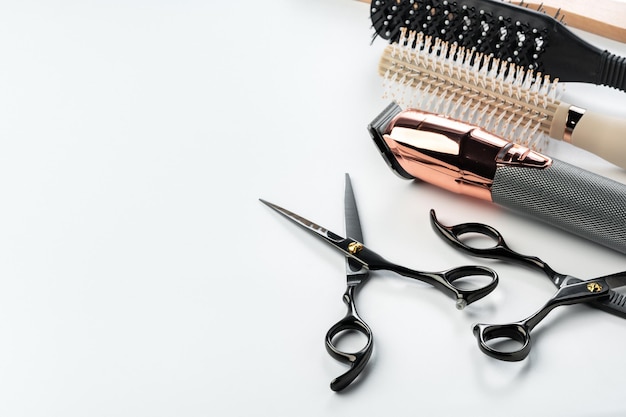 Herramientas negras para la peluquería y diversos cepillos para el cabello sobre fondo blanco