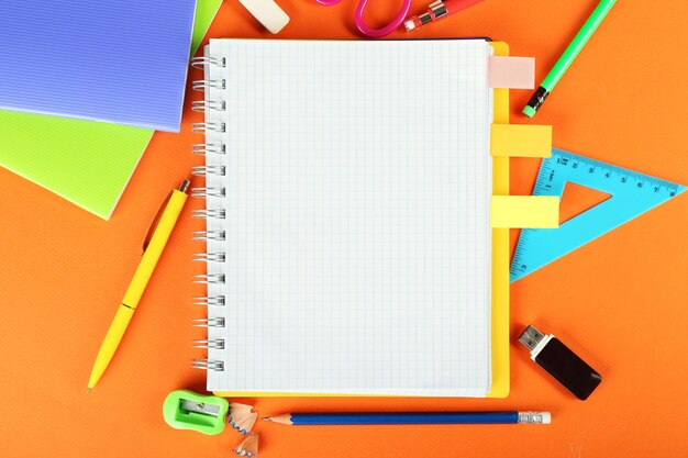 Herramientas de oficina y estudiante sobre fondo naranja primer plano