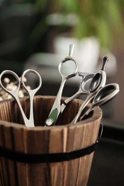 Herramientas de peluquería tijeras closeup en un jarrón de madera