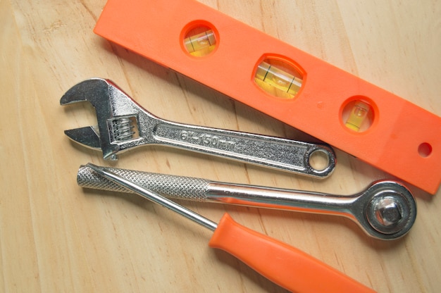 herramientas de trabajo color naranja sobre madera., destornillador, llave inglesa, nivel, etc.
